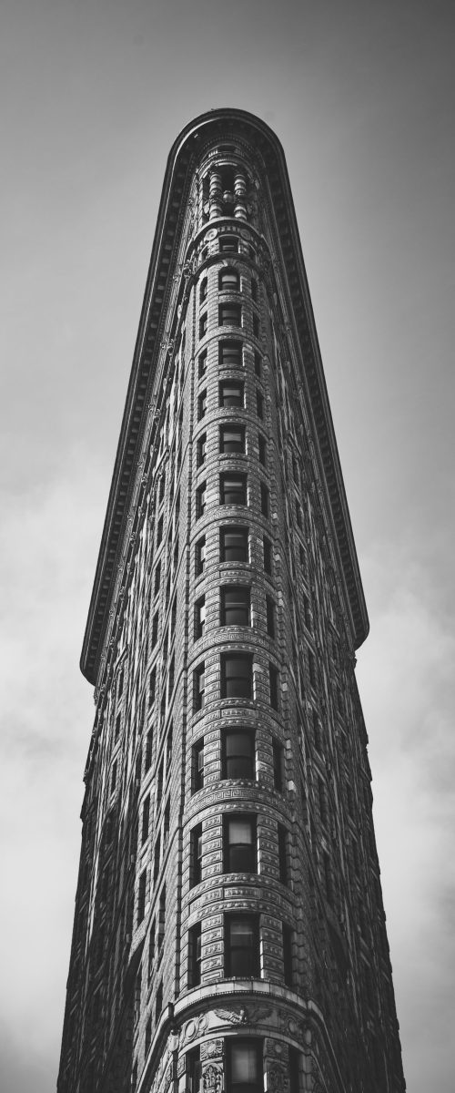 A low angle grayscale shot of the curious Flatiron Building in Manhattan, New York City, USA